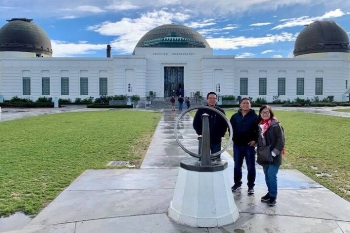 Three people posing in front of a large observatory building.