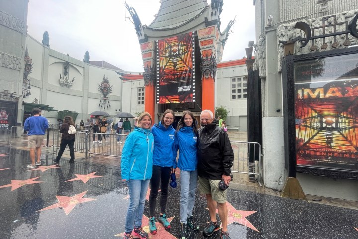 Four people at a famous theater's star-studded walkway, wearing casual outfits.