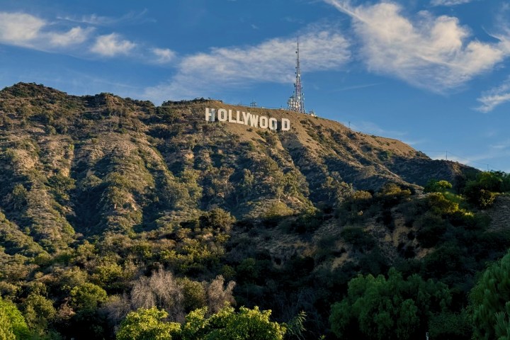 The Hollywood sign on a sunny hillside with scattered clouds in the sky.