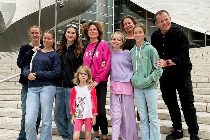Group of eight adults and children on modern building steps.