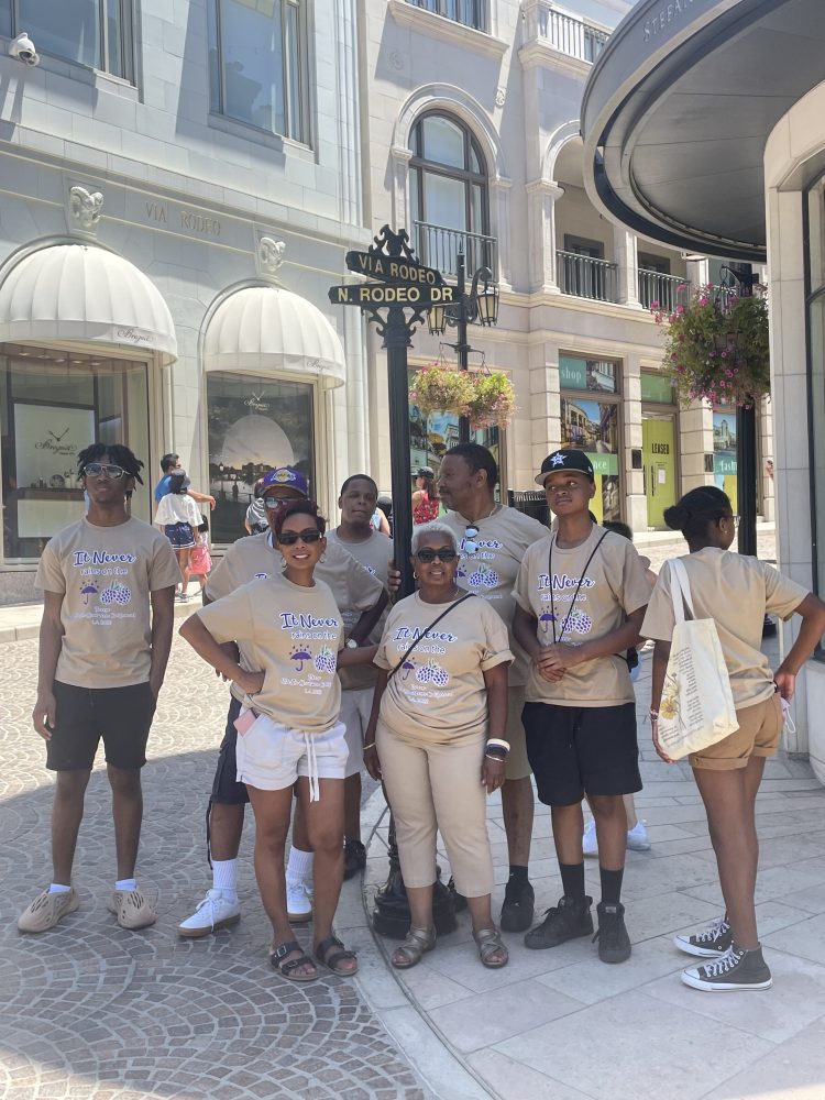 Family posing at the Via Rodeo and North Rodeo Drive street sign in Beverly Hills