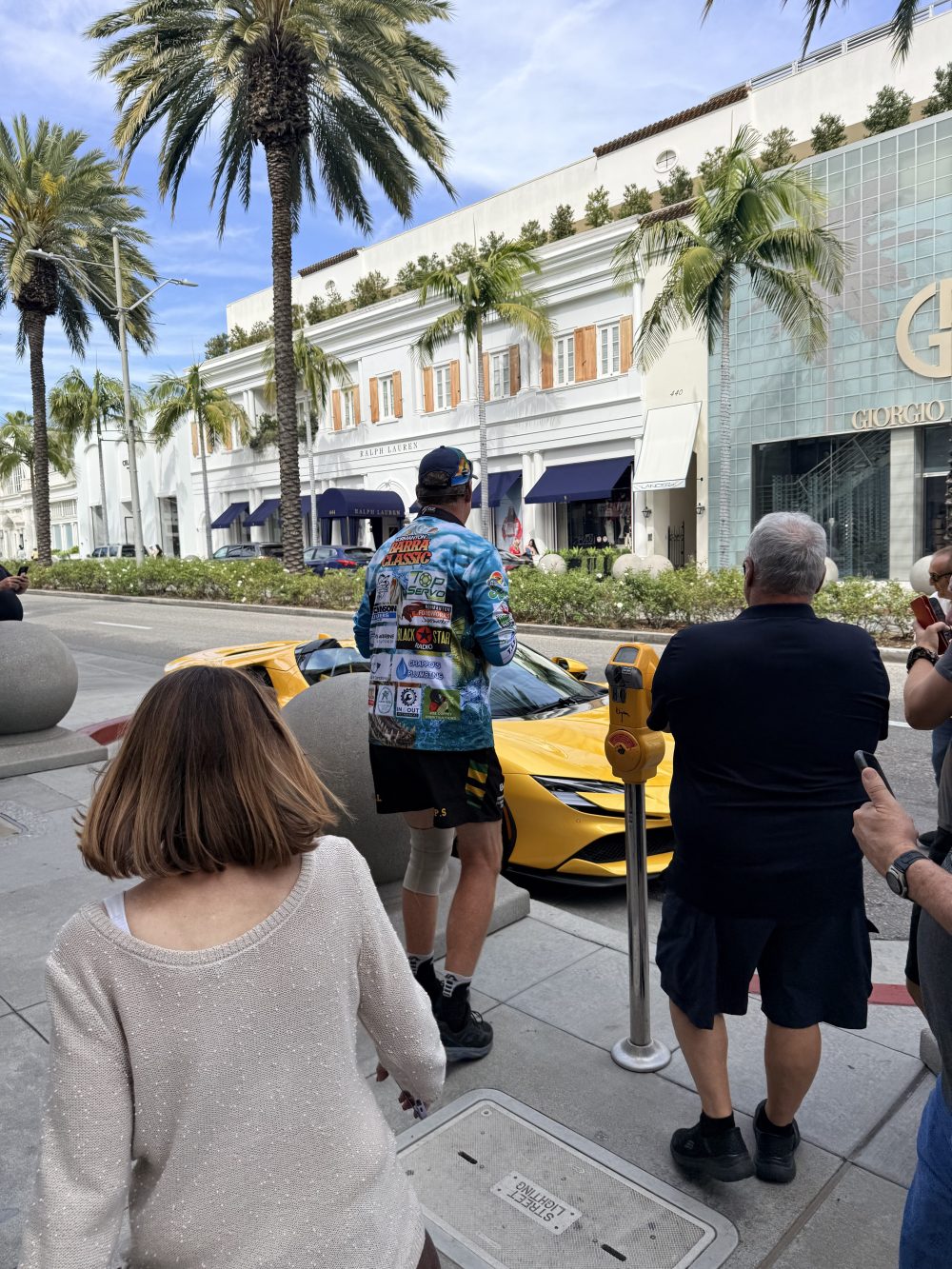 Visitors walking Rodeo Drive past the Bijan storefront and its yellow Rolls-Royce