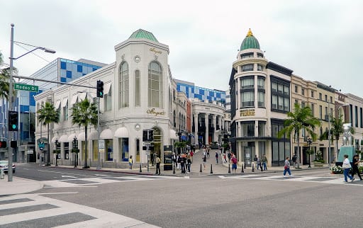 Busy street intersection with luxury shops and people walking.