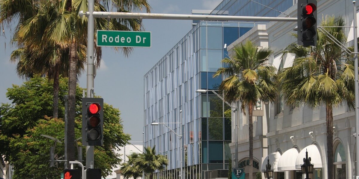 Street view of Rodeo Drive with palm trees and modern buildings.