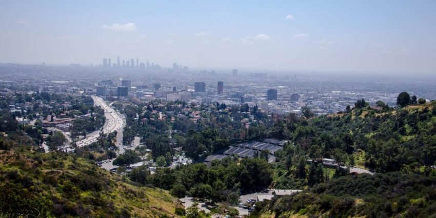City skyline view with highways and greenery in foreground on a hazy day.