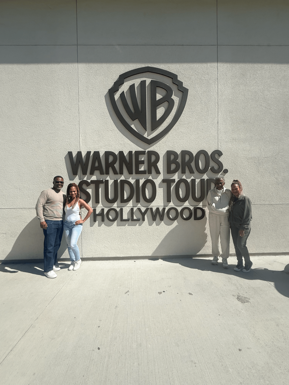 Family posing at the Warner Bros. Studio sign in Burbank during a private Los Angeles tour.