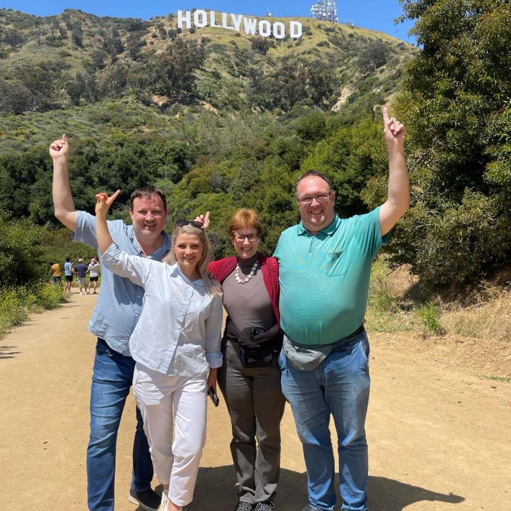 Four guests enjoying a private Los Angeles tour with the Hollywood Sign behind them